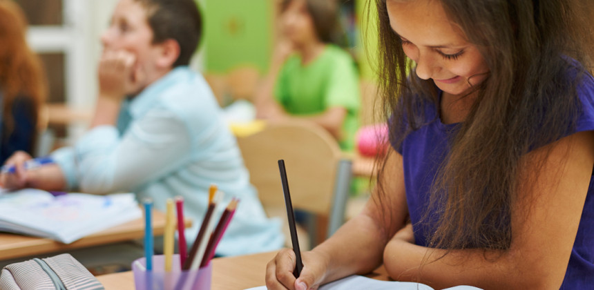 Little girl hand writing on paper in class