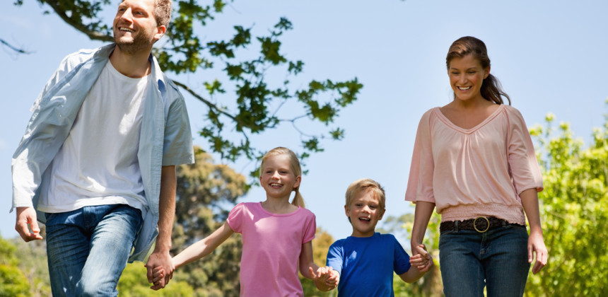 Nuclear family walking busily through a park