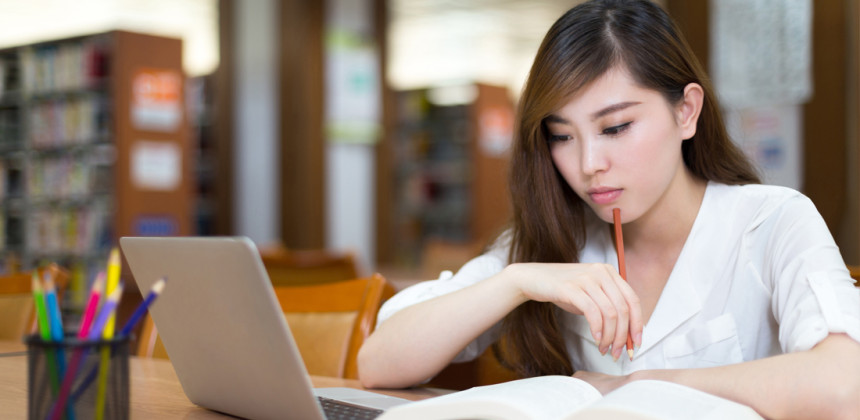 A student writing an essay in the library