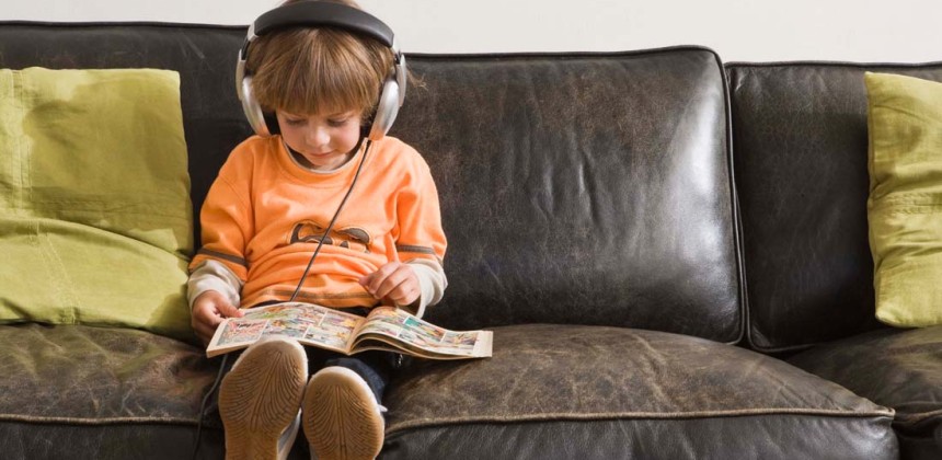 Child reading a comic book on a coach