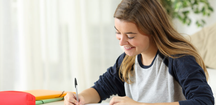 Student taking notes in a notebook in her home