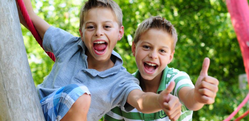 Two boys outside giving thumbs up