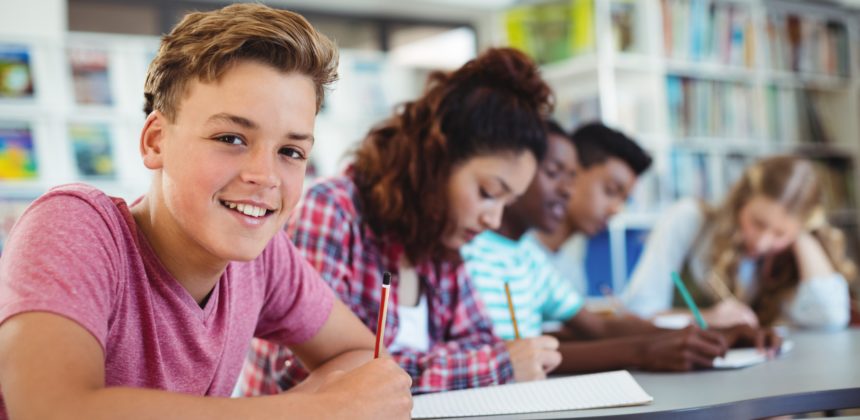 Students studying in library with boy smiling