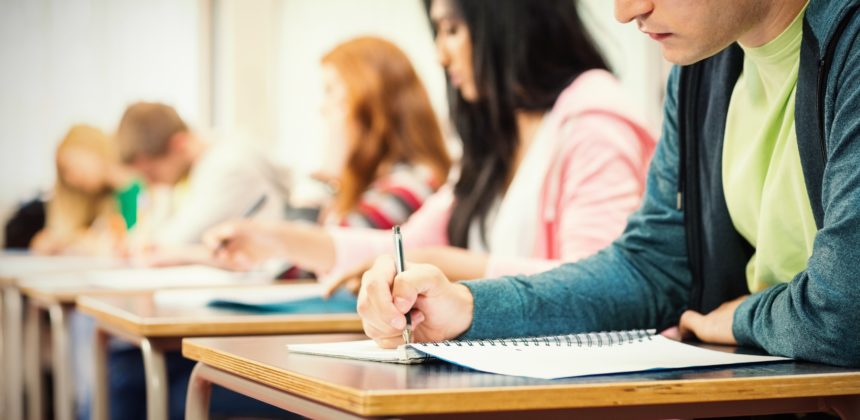 Closeup of high school students writing notes in classroom