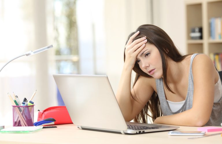 High school girl looking stressed at desk with her laptop