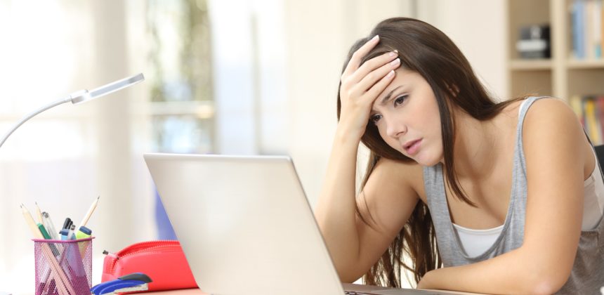 High school girl looking stressed at desk with her laptop