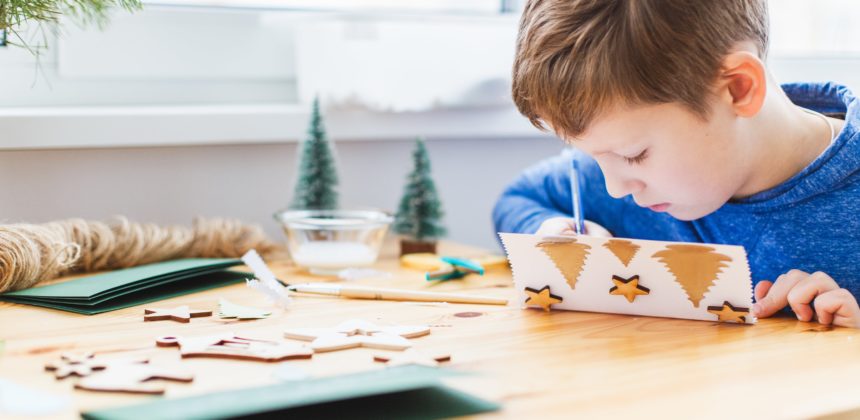 Young student at desk making a holiday card.