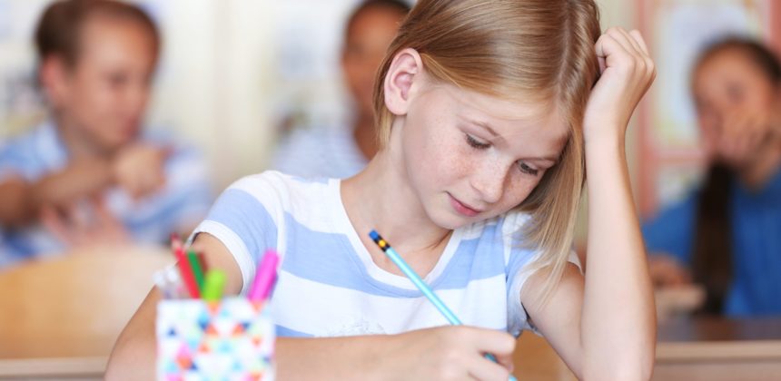 Young girl in classroom writing.