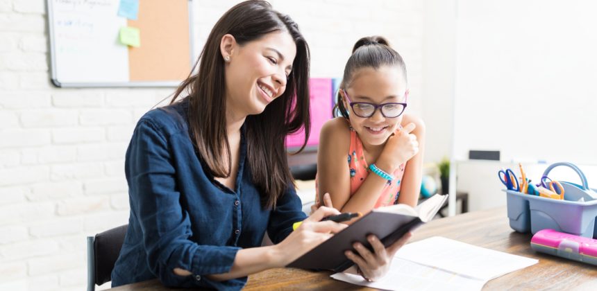 A young female student reading a book with her tutor.