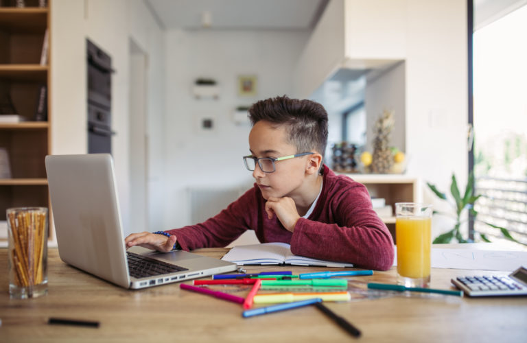 Focused child sitting at a computer at home visiting an online tutoring website
