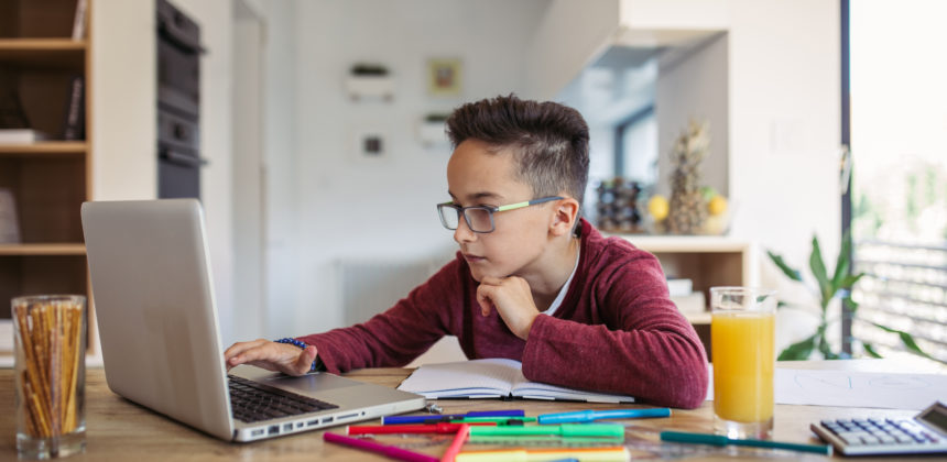 Focused child sitting at a computer at home visiting an online tutoring website