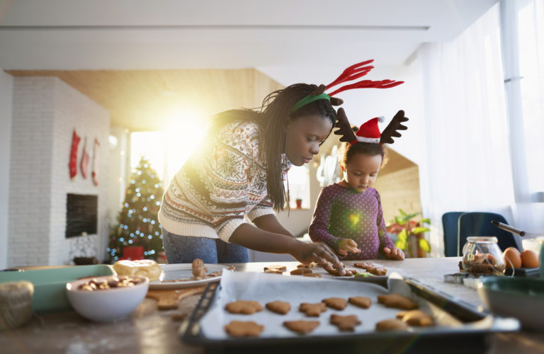 Parent and child baking holiday treats, while wearing festive outfits.