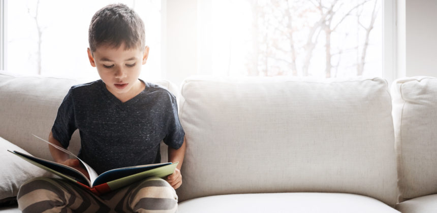 Child reading a book on a couch